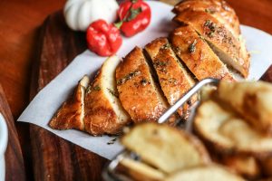 Savory sliced chicken breast with herbs, beautifully styled on a wooden board for culinary appeal.
