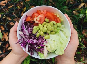 A vibrant bowl of fresh garden salad featuring tomatoes, edamame, and cabbage. Perfect for healthy dining.